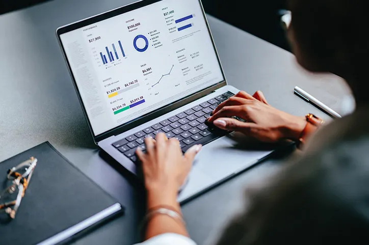 Eine Frau sieht sich grafische Darstellungen von Finanzen auf einem Laptop an