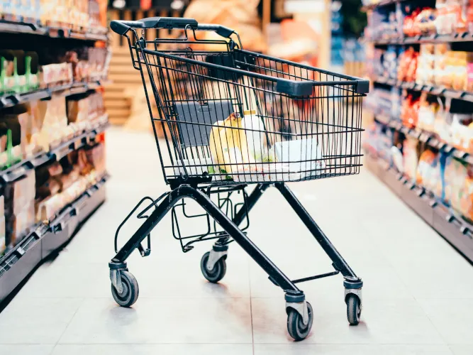 Einkaufswagen steht im Gang eines Supermarktes
