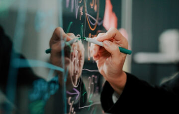 Eine Person schreibt auf eine Glastafel